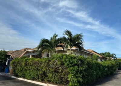 Front view of a residential house with palm trees and bushes