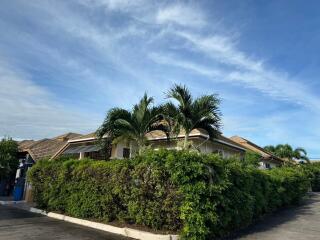 Front view of a residential house with palm trees and bushes