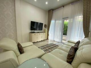 Modern living room with white leather furniture and a wall-mounted TV