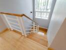 Well-lit staircase with wooden steps and white railing