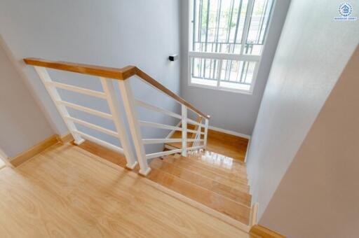 Well-lit staircase with wooden steps and white railing