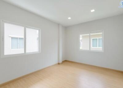 Empty bedroom with wooden flooring and two large windows