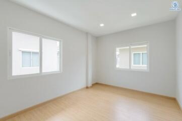 Empty bedroom with wooden flooring and two large windows