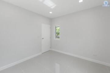 spacious empty bedroom with white door and small window