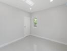 spacious empty bedroom with white door and small window