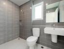 Modern bathroom with grey tiled walls and white fixtures