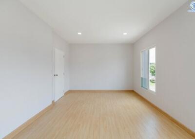 Spacious empty bedroom with wooden flooring and white walls