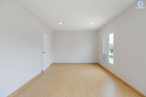 Spacious empty bedroom with wooden flooring and white walls