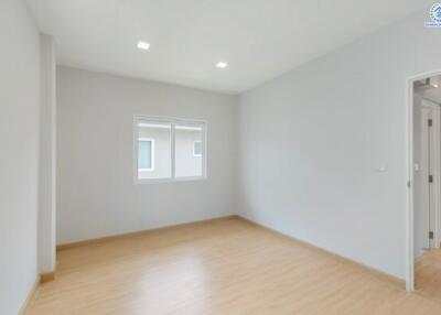 Empty bedroom with large window and hardwood floor