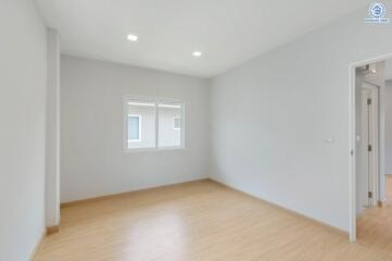 Empty bedroom with large window and hardwood floor