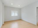 Empty bedroom with large window and hardwood floor