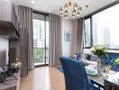 Modern living room with a view of the city, featuring a blue sofa, dining table, and wall-mounted TV