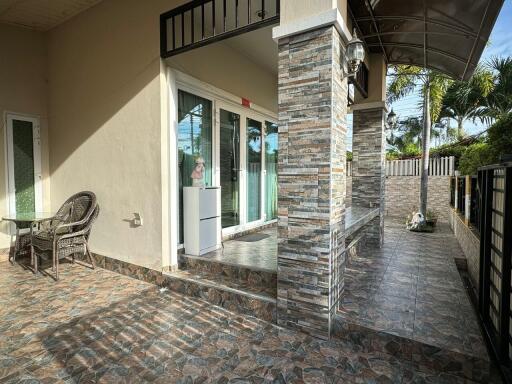 Modern outdoor patio of a building with wicker chairs, a glass table, and stone tile flooring