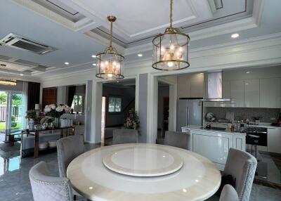 Dining area with round table and chairs, adjacent to open modern kitchen