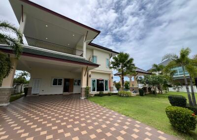 Exterior view of a two-story house with a tiled driveway and landscaped garden