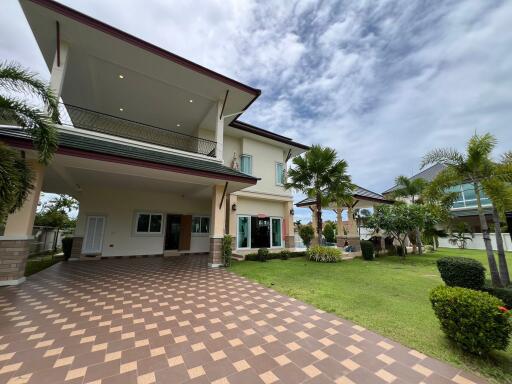 Exterior view of a two-story house with a tiled driveway and landscaped garden