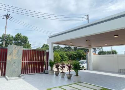 Covered carport area with tile flooring and potted plants