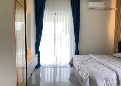 Well-lit bedroom with a bed, curtains, and air conditioning unit