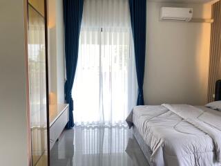 Well-lit bedroom with a bed, curtains, and air conditioning unit