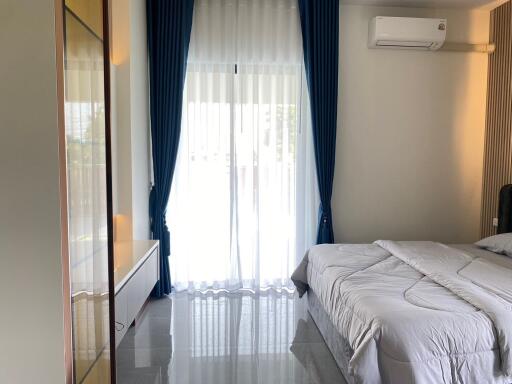 Well-lit bedroom with a bed, curtains, and air conditioning unit