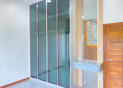 Modern bedroom with glass closet doors and wooden accents