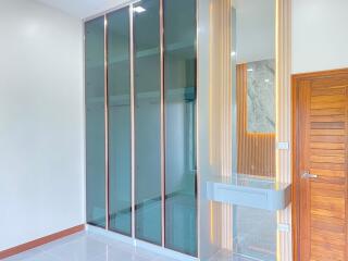 Modern bedroom with glass closet doors and wooden accents