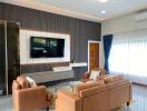 Modern living room with brown leather sofas, wall-mounted TV, and large window