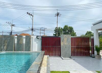 View of a modern swimming pool area with a privacy fence and an outdoor shower