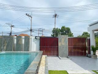 View of a modern swimming pool area with a privacy fence and an outdoor shower