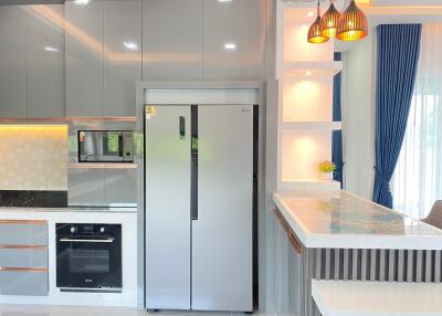 Modern kitchen with grey cabinets, stainless steel refrigerator and oven, and a breakfast bar