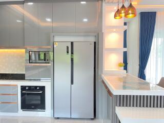 Modern kitchen with grey cabinets, stainless steel refrigerator and oven, and a breakfast bar