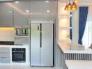 Modern kitchen with grey cabinets, stainless steel refrigerator and oven, and a breakfast bar