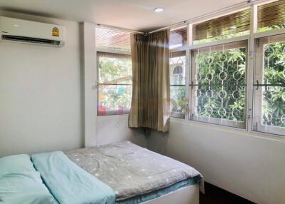 Spacious and well-lit bedroom with large windows and air conditioning