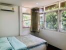 Spacious and well-lit bedroom with large windows and air conditioning