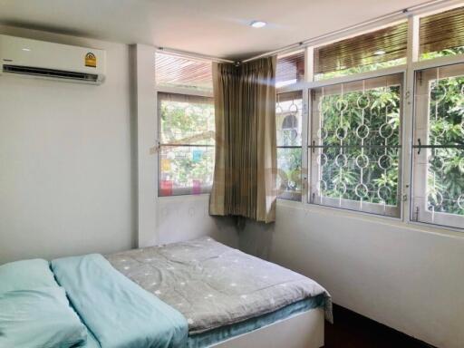 Spacious and well-lit bedroom with large windows and air conditioning