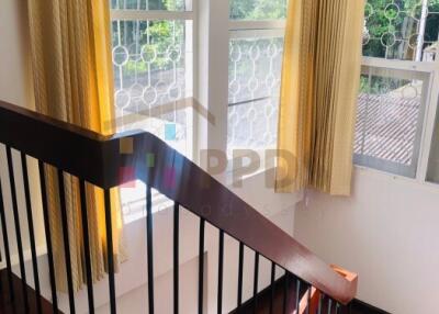 Staircase with wooden steps and metal railings, large windows with curtains, and natural light