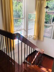 Staircase with wooden steps and metal railings, large windows with curtains, and natural light