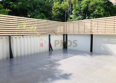 Spacious outdoor patio with tiled flooring and privacy fencing surrounded by trees