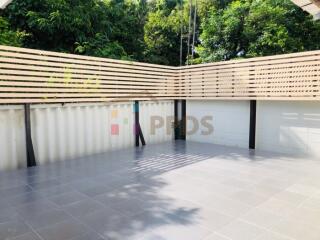 Spacious outdoor patio with tiled flooring and privacy fencing surrounded by trees