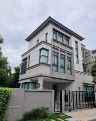 Modern multi-story residential building with large windows and a gated entrance