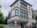 Modern multi-story residential building with large windows and a gated entrance