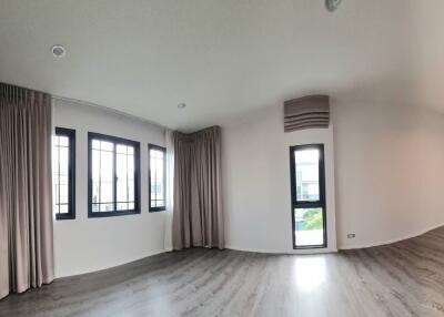 Well-lit empty living room with large windows and wooden flooring