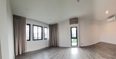 Well-lit empty living room with large windows and wooden flooring