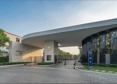 Modern building entrance with large curved roof and gated driveway