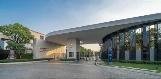 Modern building entrance with large curved roof and gated driveway