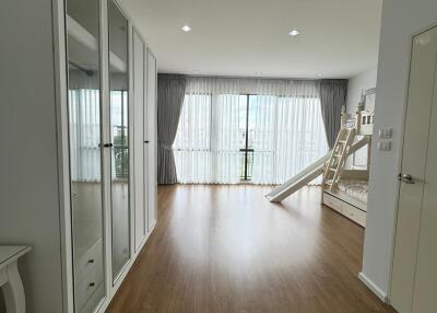 Spacious bedroom with wooden flooring, large windows, and a bunk bed