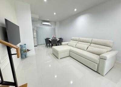 Modern living room with a mounted TV, comfortable gray sectional sofa, dining table, and minimalist decor