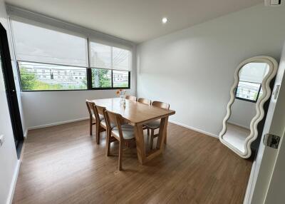 Dining room with wooden table and chairs, large windows, and decorative mirror