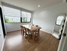 Dining room with wooden table and chairs, large windows, and decorative mirror