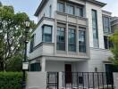 Front view of a modern multi-story house with large windows and a gated driveway